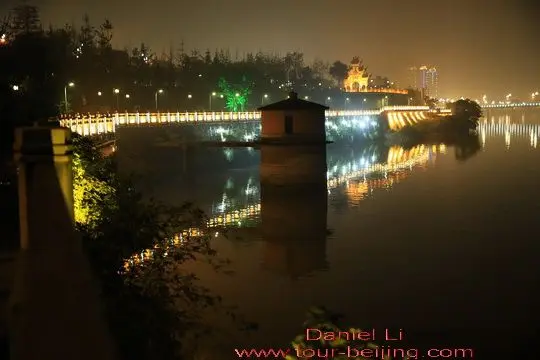 The the concrete guardrails are lit outside with their reflections on the river