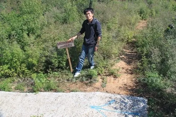 A sign board and a painted blue arrow pointing to the way to the Ming Dynasty Wall.