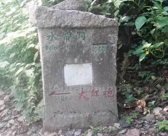 a stone sign appoiting to the right up to Water Curtain Cave and the left down to Da Hong Pao.