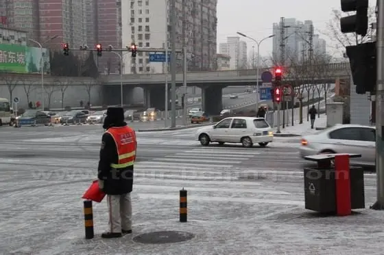 A dutiful warden is standing at his post guiding the traffic.