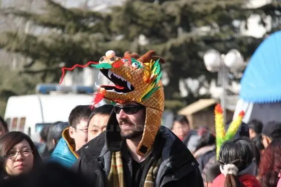 A foreigner with a dragon hat drops is lost in the sea of people