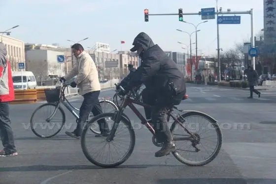 A heavily clad rider is riding on a street.
