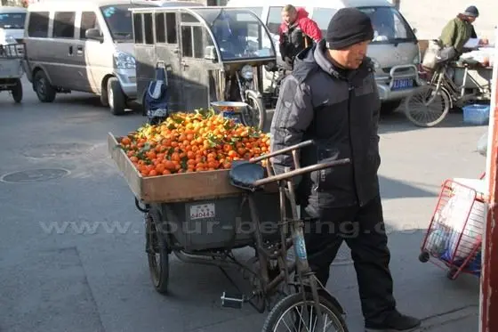 A vendor with a pedicab of oranges