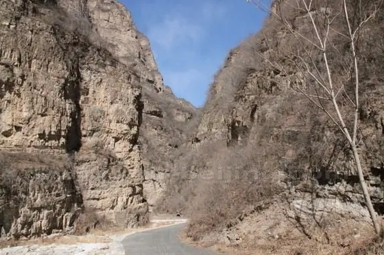A well paved road snakes through the narrow bottom of the valley.