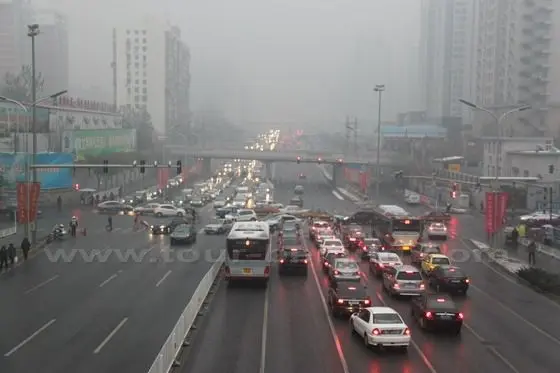 All the buses and cars are driving in the foggy and gloomy day.