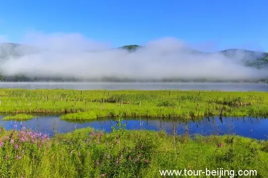 White fog and clouds hovering over the mountains and the lake