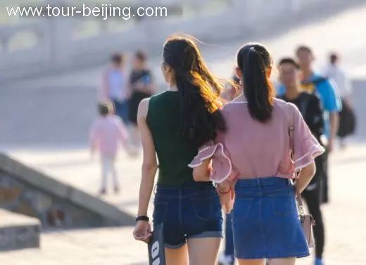 Two fashion girls hand in hand viewed from behind.