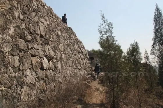 Hiking along the mountain path by the slab built wall