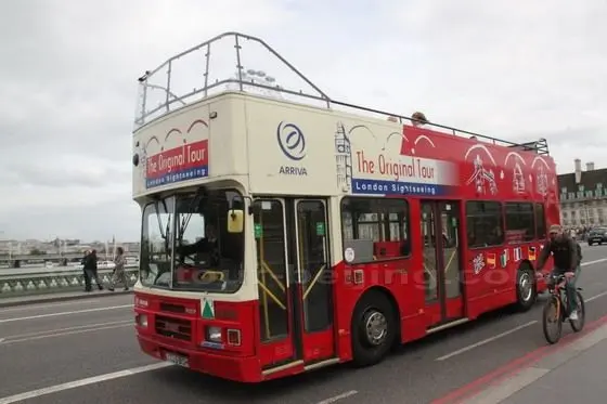 The Orignal Bus is passing a bridge over the Thames River
