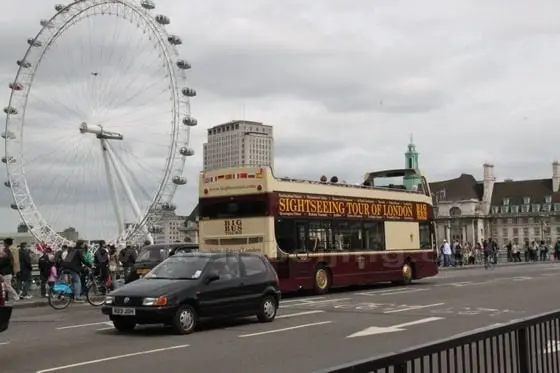 The Big Bus is passing a bridge over the Thames River with the background of the Eye of London