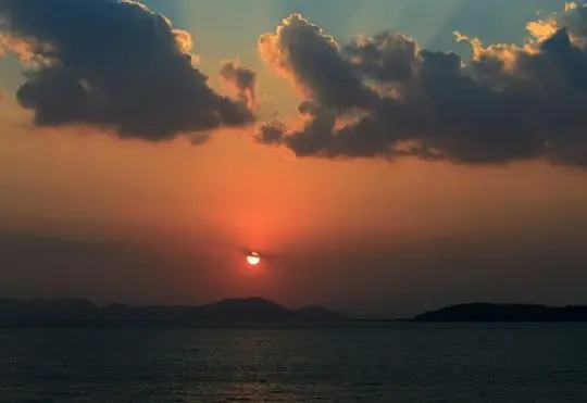 The Sun is appearing above the lake.