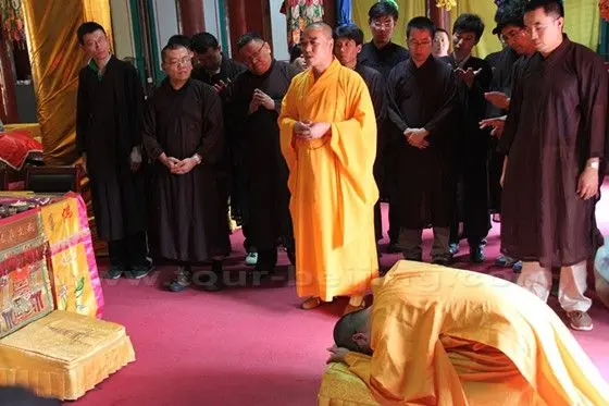 The master teaches people how to pray before Buddha in a temple
