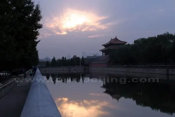 The red sunrise rays cut through the thick clouds with pretty reflections on the moat.