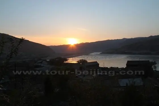 The sun is setting over the undulating mountain and the narrow riverbed of the Yellow River