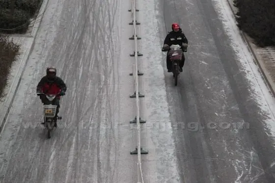 Two electric bike riders are braved the cold wind on the snow sidewalk
