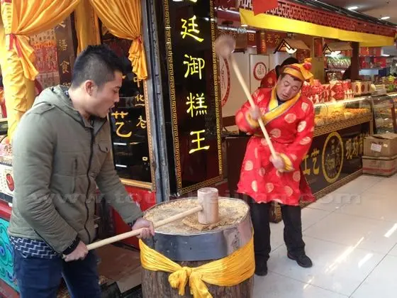 Two guys with huge wooden mallets are pounding a piece of cake