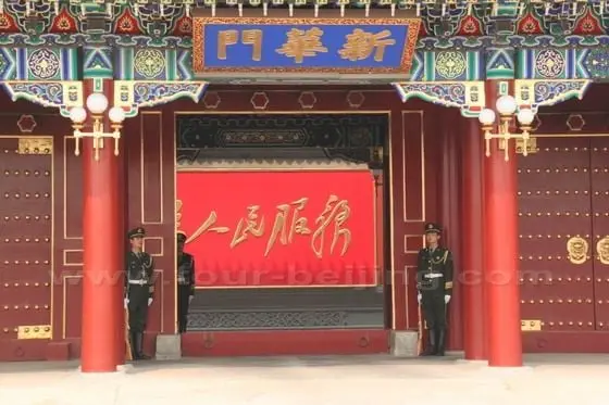 Two soldiers standing by the Xinhuamen Gate. The view inside is blocked by a wall with the sologan - Serve the People.