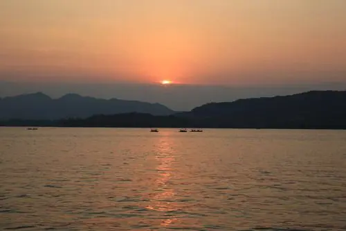 The boats are cruising on the reddish surface of the lake