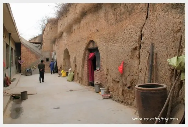 A big courtyard yard bookended by a loess hill with two carved cave houses.