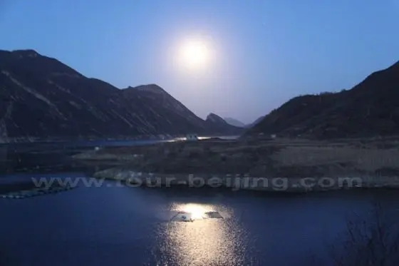 a round and bright moon hanging high in the sky over the mountains