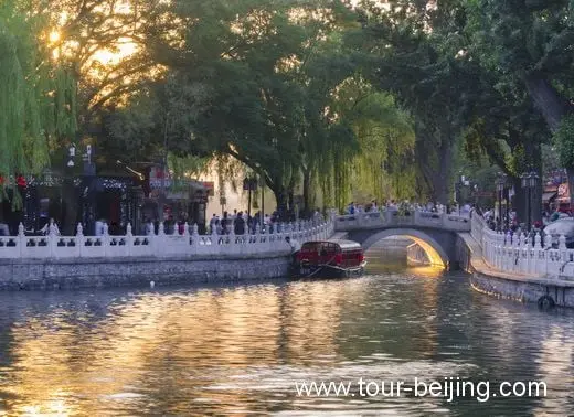 The golden and orange sunrays shine through the one- arch-bridge